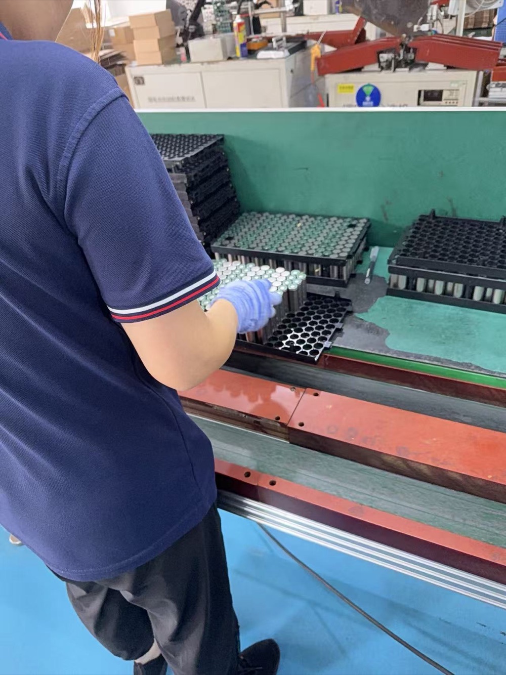 Operator handling cylindrical battery cells in trays